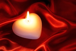 Heart shaped candle on red silk